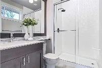 Modern vanity-integrated surround featuring a continuous, grout-free solid-surface panel that transitions seamlessly from the vanity deck directly into the shower wall.