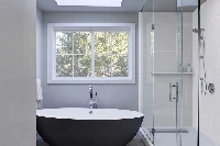 Contemporary multi-sided enclosure with sturdy monolithic panels that protect corner walls around a freestanding tub installation