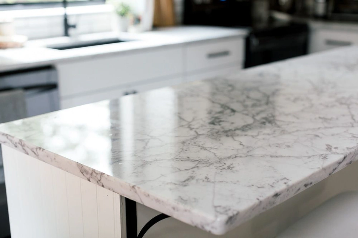 Modern waterfall island countertop featuring a seamless vertical extension that flows from the surface to the floor for a monolithic, architectural silhouette