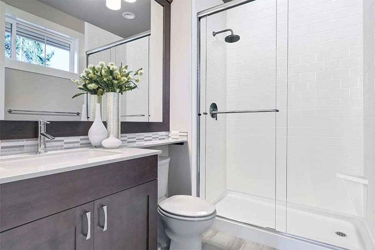 Modern vanity-integrated surround featuring a continuous, grout-free solid-surface panel that transitions seamlessly from the vanity deck directly into the shower wall.